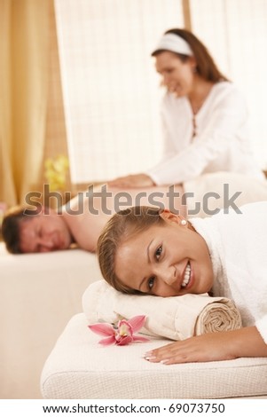 Happy couple getting back massage in day spa.