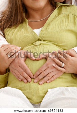 Hands of dad on mum's pregnant belly, woman holding man's hands.?