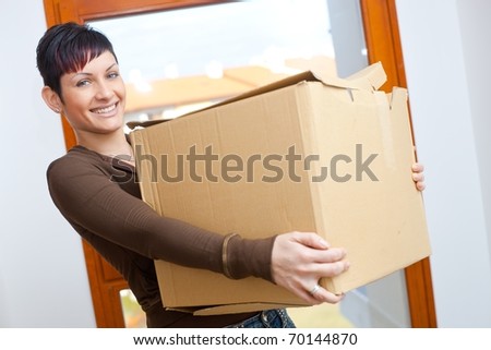 Woman lifting cardboard box while moving home, smiling.?