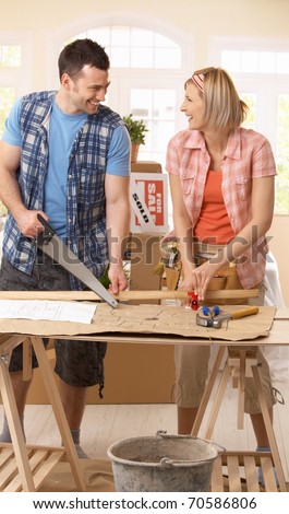 Happy couple improving new house, working together at table.?
