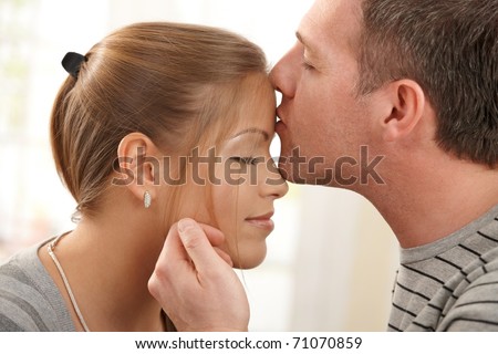 Portrait of happy couple in love, man kissing woman on forehead, stroking face with eyes closed.?