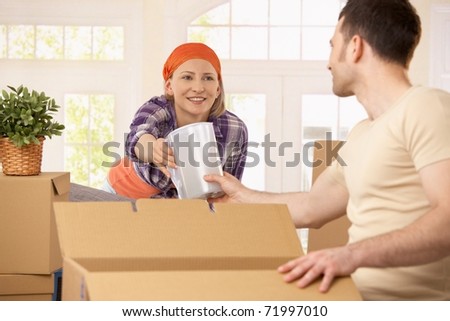 Happy couple packing boxes together to move house.?