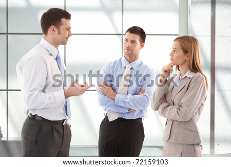 Young attractive casual office workers talking in hallway.?