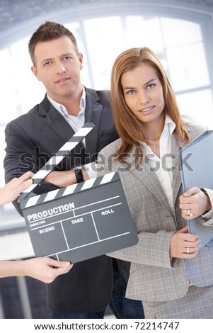 Attractive businesspeople with clapper board, during shooting a film, smiling.?