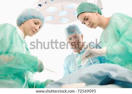 Medical team in uniform working together in operating room.?