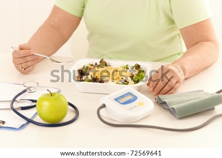 Elderly woman eating healthy diet, salad and apple.?