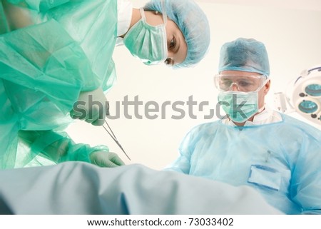 Doctors in uniform operating patient in operating theatre.?