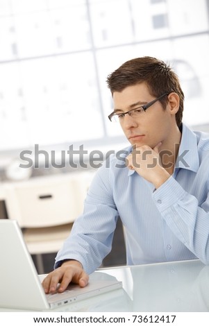 Young businessman concentrating on computer work, looking at laptop screen, thinking.?