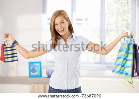 Happy woman standing arms wide open, holding shopping bags.?