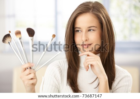 Pretty woman holding makeup brush set, smiling.?