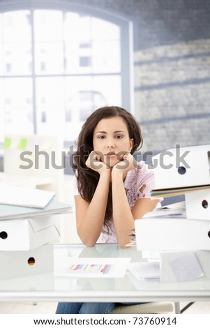 Troubled secretary sitting at desk, among folders.?