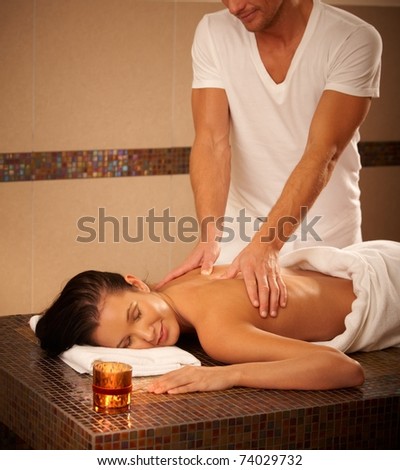 Young woman getting back massage in wellness center, relaxing with eyes closed.?