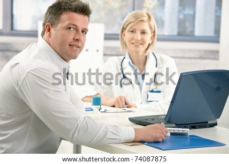 Handsome man sitting in doctor's office, smiling, on appointment with medical expert.?