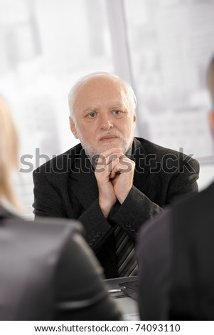 Experienced senior businessman concentrating, looking serious on meeting.