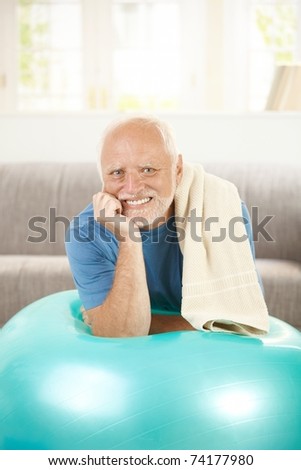 Portrait of active senior with fit ball, laying on exercise ball, smiling.?