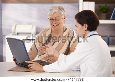 Doctor explaining results to senior patient in office, using laptop computer.?