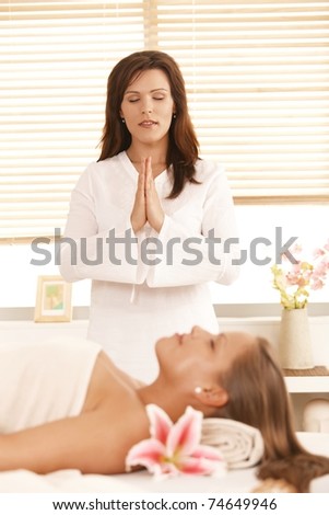 Masseur meditating over patient, before starting massage.?