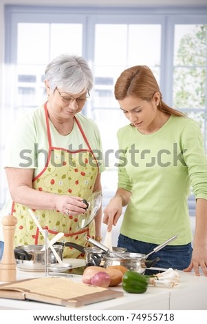Senior mother and daughter cooking together in kitchen.?