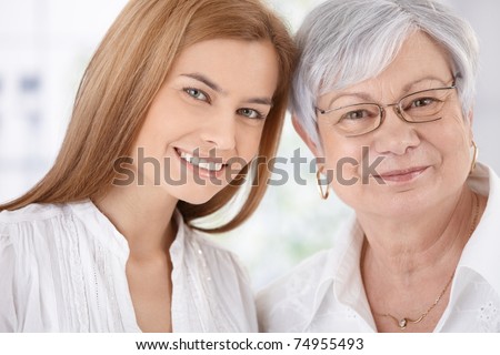 Closeup portrait of young attractive woman and senior mother, both smiling, looking at camera.?