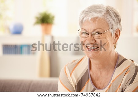 Portrait of elderly woman at home, looking at camera, smiling.?