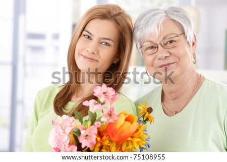 Portrait of senior mother and daughter at Mother\'s day, having flowers, smiling.?