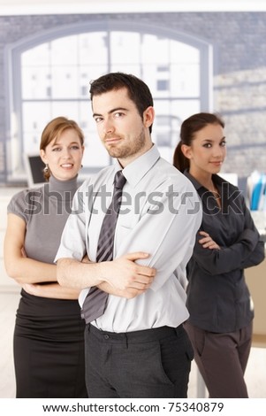 Happy team of casual office workers standing in office arms crossed.?