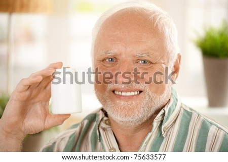 Closeup portrait of happy senior man holding medication phial, blank space.?