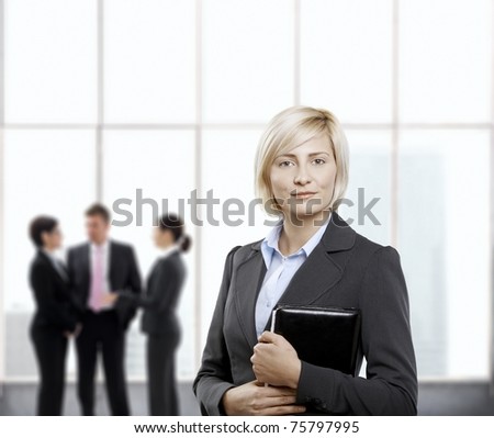 Confident businesswoman standing with personal organizer handheld in office lobby.?