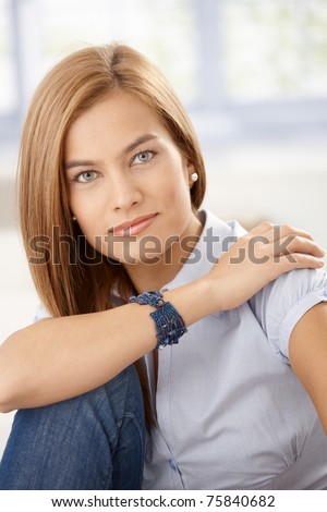 Portrait of attractive young woman sitting, hugging knees.?