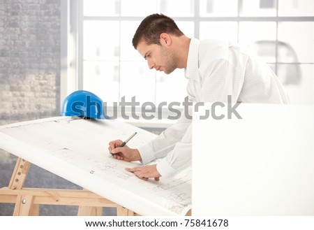 Young engineer busy by working, using drawing table.?