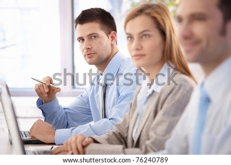 Handsome, confident businessman sitting at meeting room, having training with colleagues.?
