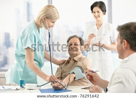 Nurse examining blood pressure for patient, doctors waiting for results.?