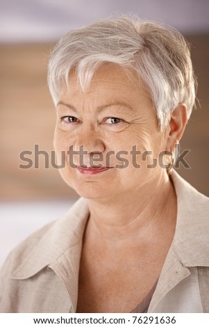 Closeup portrait of elderly woman with white hair, looking at camera, smiling.?