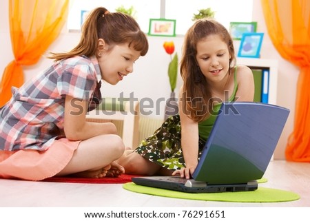 Smiling elementary age schoolchildren browsing internet on laptop computer at home.?