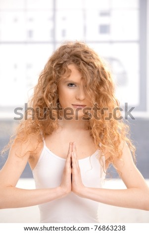 Pretty girl practicing yoga, meditating in prayer pose sitting on floor.?