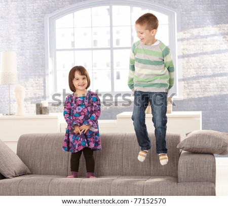 Kids playing on sofa, little boy jumping, small girl standing, laughing.?