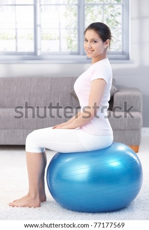 Attractive young female exercising with fit ball, smiling.?