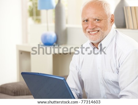 Portrait of senior man at home, having laptop computer, smiling at camera.?