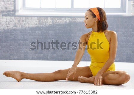 Ballet dancer concentrating on stretching on floor of art training room.?