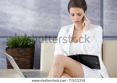 Smart businesswoman waiting in office lobby, busy working on mobile phone, using personal organizer.?