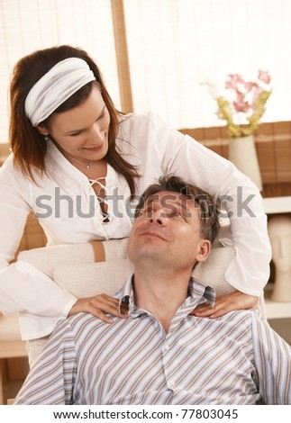 Man getting neck massage, looking up at masseur, smiling.?