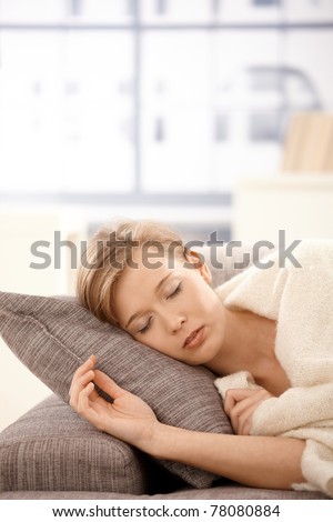 Young woman sleeping on sofa at home, covered with blanket.?