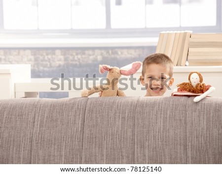 Cute little boy playing with toys at sofa, smiling at camera.?