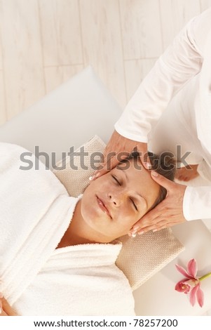 Woman getting relaxing head massage in day spa.