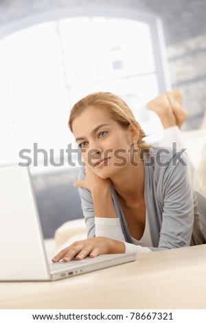 Young woman using laptop computer at at home, looking at screen.?