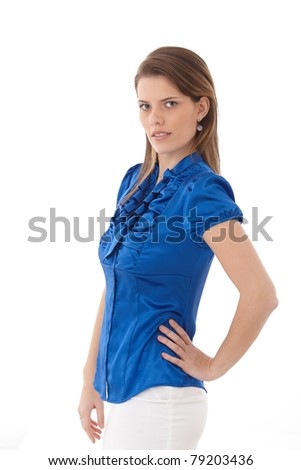 Attractive young woman posing in studio, wearing smart clothes, standing, looking at camera.?