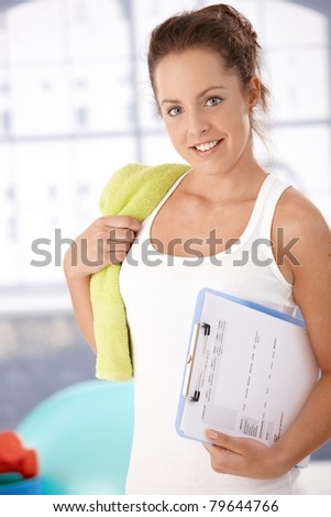 Pretty young girl prepared for personal training in gym, holding her training plan in hand.?