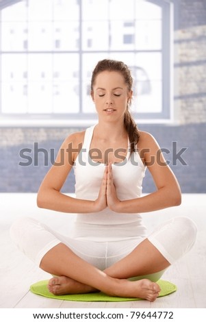 Young attractive woman practicing yoga, meditating in prayer pose in studio.?