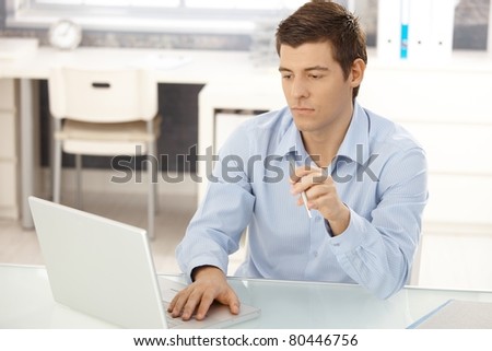 Businessman working in office on laptop computer, concentrating, looking at screen.?