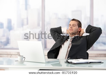 Young elegant businessman stretching on chair in office.?